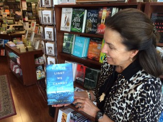 Kathleen Millard of Elm Street Books with what she calls the hottest book for summer reading, "Anthony Doerr’s “All the Light We Cannot See." Credit: Michael Dinan