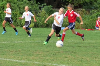 New Canaan's Caitlin Tully races past her opponent for control of the ball. Contributed photo