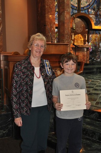 Diane Wells, Regent of the Hannah Benedict Carter Chapter of the Daughters of the American Revolution, presenting the award to St. Aloysius School fifth-grader Max Engel.