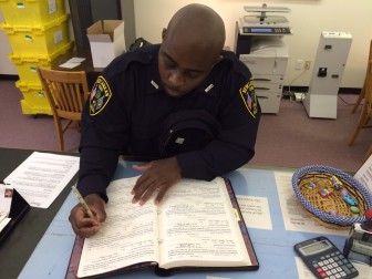 Newly sworn-in NCPD Officer Clinton Jarvis signs the oath book at the New Canaan Town Clerk's office, on April 28, 2015. Credit: Michael Dinan