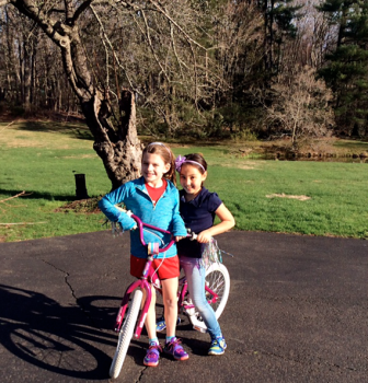 Angelina Hubertus (R) with a friend, riding bikes near the apple tree at the end of the driveway. Contributed