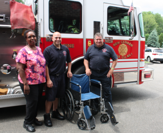 Waveny Rehab assistant Yolette Milord presents the gifted chair to New Canaan firefighters. Contributed
