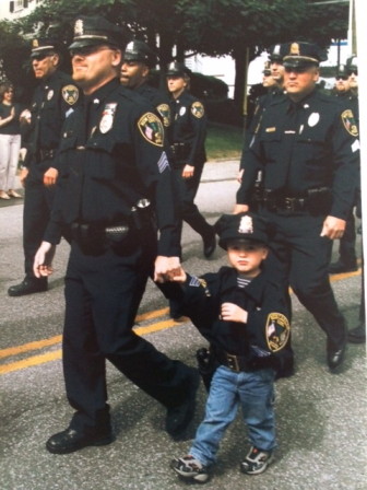 New Canaan Police Lt. Fred Pickering marches in a recent Memorial Day parade with his son. 