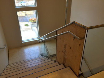 A glass pane somehow became dislodged and shattered in this stairwell at Town Hall. The contractor installed plywood as a stopgap until a new pane arrives. Officials are looking into the cause of the problem. Credit: Michael Dinan